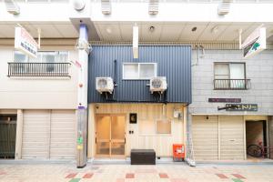 a building with two garage doors and two windows at おそば 露天風呂でリラックス ベッド7台 usjへ11分 商店街に位置するお宿 in Osaka