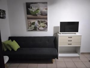 a living room with a couch and a tv on a dresser at Grand T2 avec piscine privative in Les Trois-Îlets