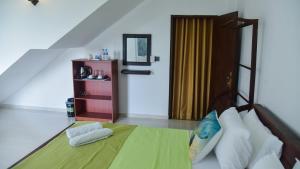1 dormitorio con 1 cama con manta verde y espejo en Sarali home stay, en Dambulla