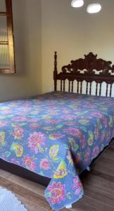 a bed with a blue blanket with flowers on it at Calmaria in Vila Velha