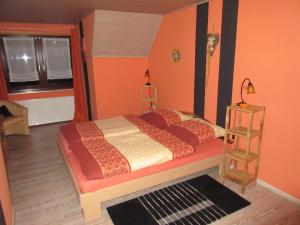 ein Schlafzimmer mit einem Bett mit orangefarbenen Wänden und einem Fenster in der Unterkunft Ferienhaus Schulze in Schierke