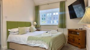 a bedroom with a bed with green curtains and a window at The Cricketers Inn in Winchester