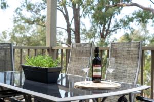 a bottle of wine sitting on a table with two glasses at Villa Above Par, Privately Managed within Cypress Lakes Resort, Premier 2 Storey Villa, 2 Bedrooms, both with Private Ensuites, Light Breakfast included in Pokolbin