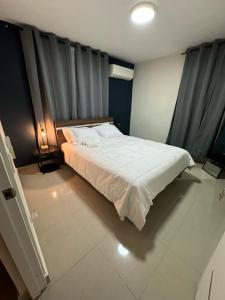 1 dormitorio con 1 cama blanca grande y cortinas grises en Solano Apartamentos, en Boca Chica