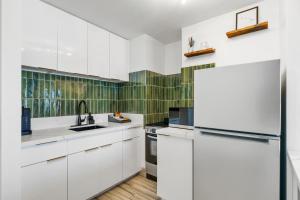 a kitchen with white cabinets and green tiles at Modern Suite Free Parking View AC King Bed Kitchen in Honolulu