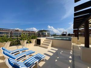 eine Terrasse mit Liegestühlen und ein Swimmingpool in der Unterkunft Awesome apartment at Aldea Thai Beachfront in Playa del Carmen