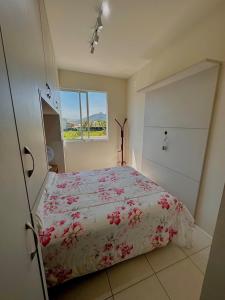 a bedroom with a bed with red flowers on it at Ap 6 minutos da Praia de São Miguel, Em Biguaçu in Biguaçu