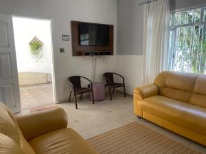 a living room with a couch and chairs and a tv at Confortável Casa em Pitangueiras no Guarujá in Guarujá