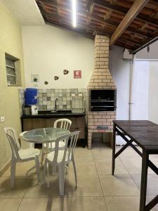 a kitchen with a table and chairs and a brick oven at Confortável Casa em Pitangueiras no Guarujá in Guarujá