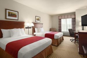 a hotel room with two beds and a desk at Country Inn & Suites by Radisson, Tifton, GA in Tifton