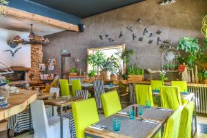 un restaurante con mesas de madera y sillas amarillas en Hôtel Green Ecolodge, en La Colmiane
