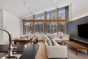 a living room with a table and a large window at Aoyama Lodge 2 in Kutchan