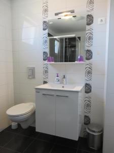 a white bathroom with a toilet and a sink at Sea Gate Studio in Zadar