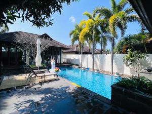 a swimming pool with palm trees and a house at 三亚亚龙湾伊墅情怀旅租 in Sanya
