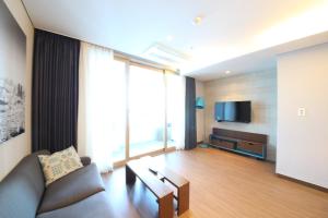 a living room with a couch and a tv at Haeundae W Residence Hotel in Busan