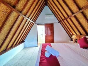 a bedroom with a white bed with a red blanket at Sunset Villa Penida by ABM in Nusa Penida