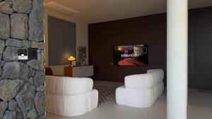 a living room with white chairs and a tv at Gosodam Yeosu in Yeosu