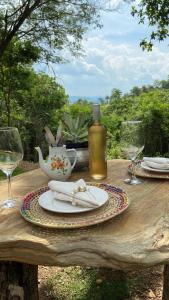 een houten tafel met borden en wijnglazen erop bij Quintal de Casa in São João Batista do Glória