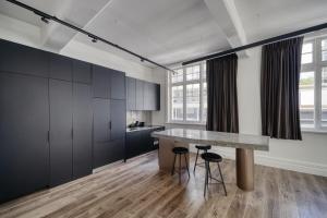 a kitchen with black cabinets and a counter with stools at High Street Luxury Loft in Auckland
