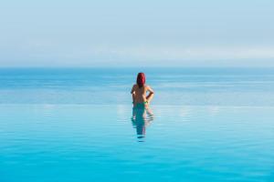 a person standing in the water in the ocean at Alia Palace Hotel - Adults Only 16+ in Pefkohori