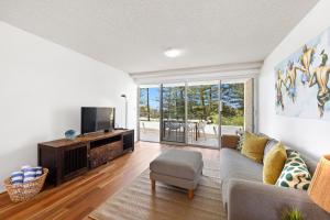 a living room with a couch and a tv at Beachfront Retreat at Burleigh, Breezy and Cosy in Gold Coast