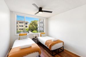 two beds in a room with a window at Beachfront Retreat at Burleigh, Breezy and Cosy in Gold Coast