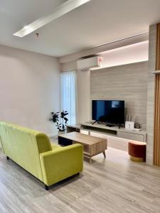 a living room with a green couch and a tv at Queensland Suites at Aru Suites, Kota Kinabalu 2 Bedroom Family Suite in Kota Kinabalu +15 photos