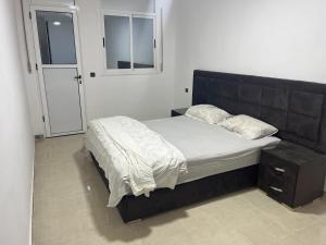 a bed with a black headboard in a bedroom at appartement neuf ideal in Monte ʼArrouit
