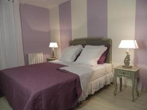 Haute-GoulaineにあるLe Logis De Saint-Martinの紫の壁のベッド1台、ランプ2つが備わるベッドルーム1室が備わります。