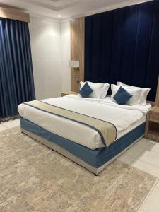a bedroom with a large bed with blue walls at أجنحة المدينة للشقق المفروشة in Al Madinah