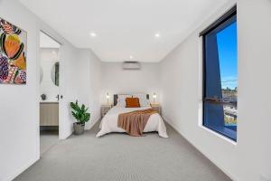 una camera da letto bianca con un letto e una finestra di Stylish Three-Story Getaway with Balcony - Clayton a Clayton North