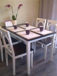 Una mesa con cuatro sillas con tazas y flores. en LD apartamenti, en Ventspils