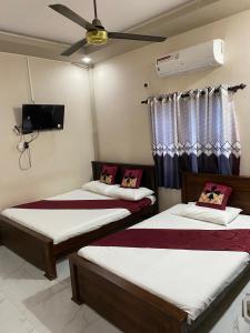 Drei Betten in einem Zimmer mit Deckenventilator in der Unterkunft Athi Hotel in Mannar