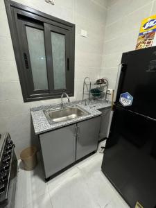 a kitchen with a sink and a black refrigerator at Hotel Apartment in Madinaty Prevado in Madinaty