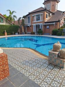 a swimming pool in front of a house at Rosie Garden & Home in Na Jomtien