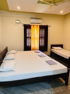 a room with two beds and a window at Shri Ganesh Residency And Restaurant in Dharmastala +5 photos