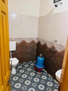 a bathroom with a toilet and a blue bucket at Shri Ganesh Residency And Restaurant in Dharmastala