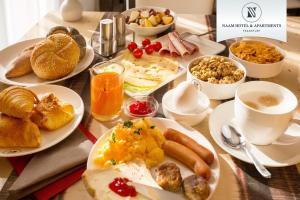 a table with plates of breakfast foods and cups of coffee at Naam Hotel & Apartments Frankfurt City-Messe Airport in Frankfurt/Main