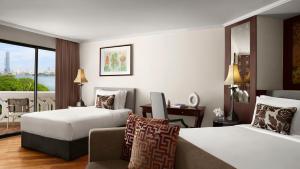 a hotel room with two beds and a couch at Anantara Riverside Bangkok Resort in Bangkok