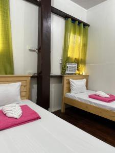 two beds in a room with green curtains at Agoo Tourist Cabin in Agoo +8 photos