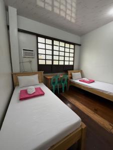 a room with two beds and a table and two chairs at Agoo Tourist Cabin in Agoo
