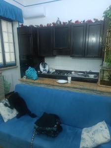 ein blaues Sofa in einer Küche mit schwarzen Schränken in der Unterkunft La Casa Dei Desideri in Oria
