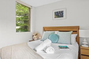 1 dormitorio con 1 cama con sábanas blancas y almohadas azules en The Botanica, en Wollongong