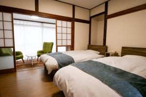 a room with two beds and a chair and a window at Family Villa KASAMA in Kasama