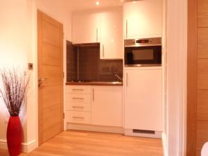 a kitchen with white cabinets and a microwave at Old School House Studio in Stetchworth