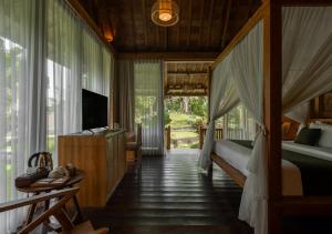 a bedroom with a bed and a television in it at Natajiwa Village in Seminyak