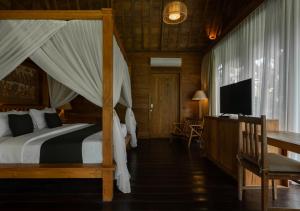 a bedroom with a bed and a desk and a television at Natajiwa Village in Seminyak
