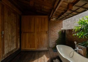 a bathroom with a wooden door and a bath tub at Natajiwa Village in Seminyak