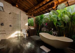 a bathroom with a tub and some plants at Natajiwa Village in Seminyak