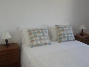 a bedroom with a bed with pillows and two night stands at Casa Mar Azul in Vila Nova de Milfontes